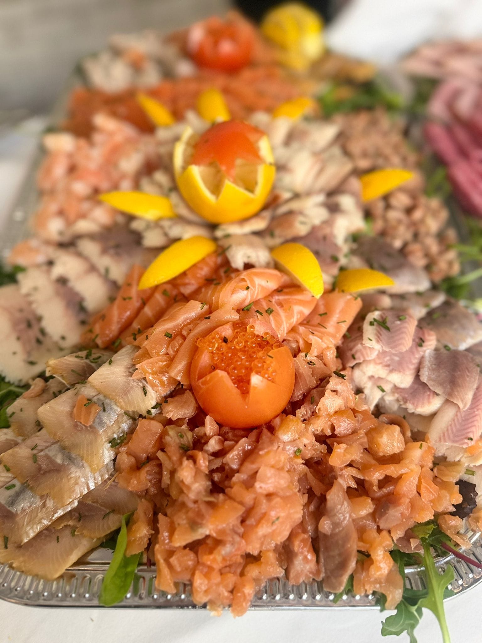 Visschotel met gerookte zalm, paling en makreel, versierd met citroen en tomaat