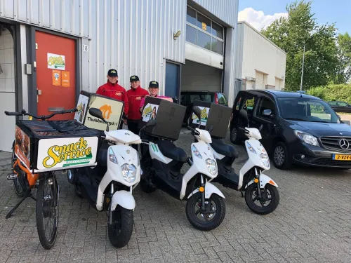 Bezorgers van Snackservice Rotterdam met scooters en een bakfiets voor het pand